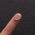 Detailed view of silver hoop earring with 11 micro-pave zircons held on a fingertip - 2# Silver