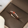 Nahaufnahme eines Roségoldrings mit rundem Rubin und Diamanten in einer Box - US 8 / Roségold