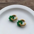 Macro detail of retro gold hoop earrings with emerald green beads on a white plate - Gold With Green Beads