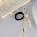 Dettaglio dell'elegante fiocco nero per capelli con perle e tipografia inglese chic - Decorazione con Fiocco e Perle / Bianco Sporco