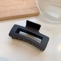 Pinza de pelo grande negra mate con diseño geométrico sobre fondo de mármol liso - Negro