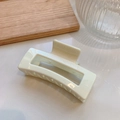 Primer plano de una pinza para el cabello cuadrada crema brillante sobre bandeja de madera - crema