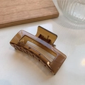 Detalle de una pinza para el pelo rectangular ámbar con fuerte mecanismo de resorte - Café Transparente