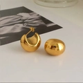 Macro-opname van minimalistische holle gouden bolletjes oorbellen met spiegelglans - Titaniumstaal / Goud (Titanium Staal)
