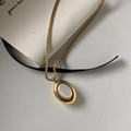Macro detail of oval gold pendant with white shell inlay and box chain on silk ribbon - Necklace / Gold