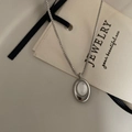 Detailed close-up of oval white shell pendant on a silver box chain with minimalist design - Necklace / Silver