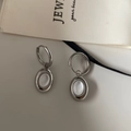 Close-up of elegant silver hoop earrings with oval white stone drop on a gift bag - Ear Buckle / Silver