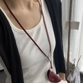 Détail de la pochette de cou en cuir bordeaux avec bouton en métal et lanière - Sac Demi-cercle Rouge