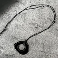 Detailed close-up of a black glazed round pendant necklace with metallic bead accents - Irregular Glass with Three Steel Beads