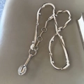Macro-detail van een zilveren lepelhanger met een geweven koord en metalen kralen - Nieuwe Beige Driestrengs Gevlochten Touw Lepel Ketting