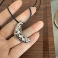 Silver croissant pendant on a black cord necklace held in hand for size and texture detail - Silver Croissant Necklace