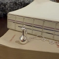 Detailansicht der silbernen Flaschen-Halskette auf Vintage-Büchern mit Perlenkette - Kugelkette Kleine Flasche / Silber