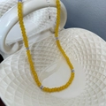 Vibrant beaded necklace with yellow beads and purple accents on a ceramic bowl - Yellow Beaded Necklace