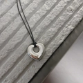 Detailed view of a polished silver heart pendant on a minimalist black cord necklace - Hollow Heart Style