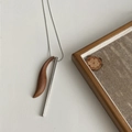 Detail view of crescent ebony wood and polished steel cylinder pendants on long chain - Walnut Wood (Stainless Steel Chain)
