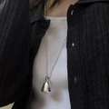 Macro shot of silver acorn pendant with vertical texture on dark textured sweater - Crystal Pine Cone Style