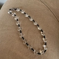 Kralenketting met transparante hartvormige bedels en zwarte kralen op beige stof - Zwarte Kraal Hart Halsketting
