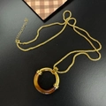 Minimalist gold necklace with amber resin circle pendant on a polished metal chain - Gold