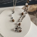 Collar bohemio con cuentas ojo de tigre y perlas en un plato de cerámica blanca - Estilo de Cuentas con Textura de Ojo de Tigre