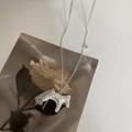 Detail view of silver dala horse pendant with fringe tassels on a floral card - Matte Silver Tassel Horse Long Necklace