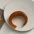 Thick amber resin open cuff bracelet with natural marbled texture on ceramic tray - Coffee Brown Moon Bangle