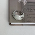Close-up of light green enamel open ring with 3D silver heart charms on a book edge - Cream White Multi-Heart Metal Decor Style