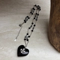 Close-up of black heart cross pendant with silver floral detail on vintage bead chain - Black