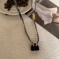 Detail der Tigerauge-Perlen-Quastenkette mit schwarzem handtaschenförmigem Anhänger - Obsidian-Stil