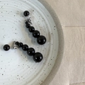 Detail von Ohrhängern mit schwarzen Achatperlen auf einem minimalistischen Keramikteller - Schwarze Perlenohrringe