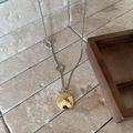 Detailed close-up of a dual-tone oval pendant on a silver chain over a stone surface - OT Buckle / Gold
