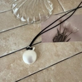 Detailed view of an elegant pearlescent oval bottle pendant on a minimalist black woven cord - Black Rope / Matte Silver