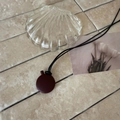 Macro detail of a minimalist matte dark red circular pendant on a sleek black cord necklace - Black Rope / Red