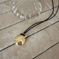 Detailed view of an oval gold perfume bottle pendant on a black cord necklace - Black Rope / Gold