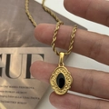 Close-up of vintage 18K gold plated stainless steel necklace with black stone and sunburst relief - Rope Chain With Vintage Black Oval Pendant