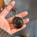 Irregular resin black pendant necklace with silver edge and snake chain on model hand - Greyish Black With Adjustable Steel Chain