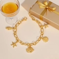 Golden stainless steel ocean charm bracelet featuring starfish and shell pendants in a gift box - Bracelet