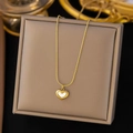 Gros plan d'un collier cœur doré avec nacre blanche sur un support à bijoux - Collier Cœur en Nacre Blanche (QYH65) / Or