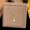 Elegant gold knot necklace with a white teardrop pearl pendant displayed on a jewelry box - Knot Pearl Style / Gold