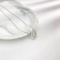Minimalist silver horseshoe U-pendant snake chain necklace on a white marble tray - Steel