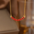Golden curved necklace featuring eleven vibrant red crystals in a horizontal arch design - Gold Red Zirconia