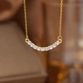 Macro shot of gold necklace with a curved smile pendant set with clear crystals - Gold White Zirconia