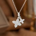 Silberne Halskette mit doppeltem Kleeblatt, Pavé-Kristallen und poliertem Blumenanhänger - Silber