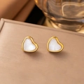 Close-up of heart-shaped gold stud earrings with white inlay on a luxury jewelry box - Stud Earrings / White Heart Stud Earrings
