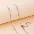 Gros plan d'un collier triple couche en acier inoxydable argenté à perles espacées - Collier Simple Couche (H6090) / Argent