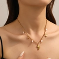 Gold multi-charm necklace with dolphin, starfish, and baroque pearl detail on a model - Necklace