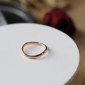 Elegant rose gold wave ring on white display stand with blurred red roses background - US 6 / Rose Gold