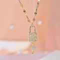 Golden titanium necklace featuring a sparkling zircon padlock and clover key pendant - Gold