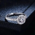 Luxurious round 1 carat moissanite ring with halo setting on a blue textured background - Halo Round Style / Silver