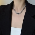 Detail shot of a silver curb chain necklace with a black square pendant on a suit - Silver Necklace
