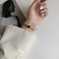 Fashionable gold chunky chain bracelet with black square charm on woman's wrist - Gold Bracelet